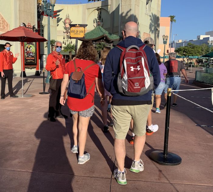 Guests walking toward a Hollywood Studios attraction wearing backpacks
