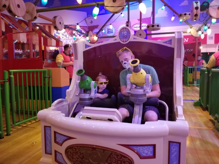 A dad and his daughter on the Toy Story Mania ride vehcile