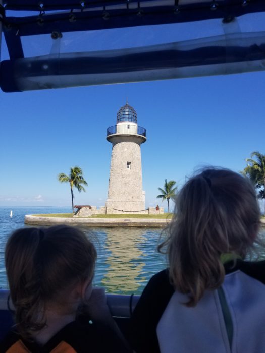Two small children look at a lighthouse in the background