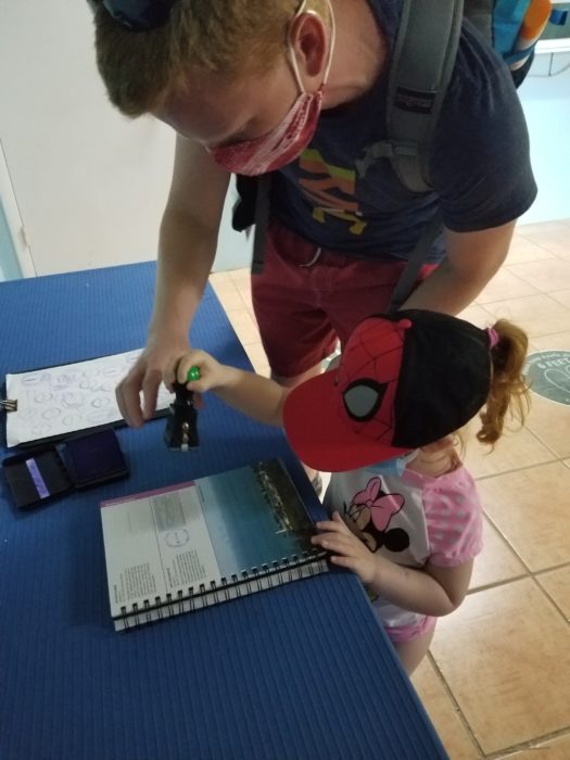 A father helps his small daughter to stamp her national parks passport book