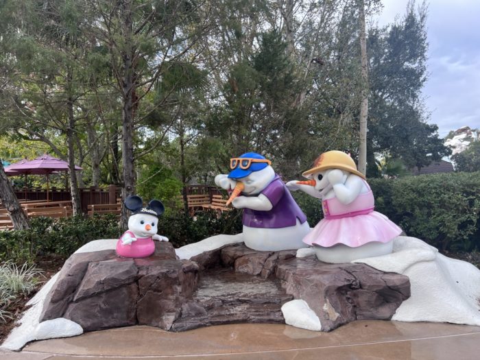 Repainted snowmen in pink, purple, and blue sit along a walkway to the water slides.