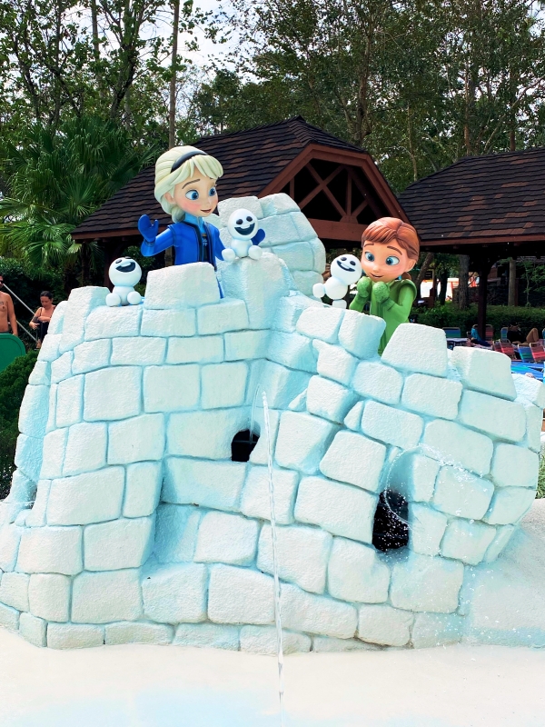 Anna and Elsa, as small children, build a lopsided snow castle at Tikes Peak in Disney's Blizzard Beach water park.
