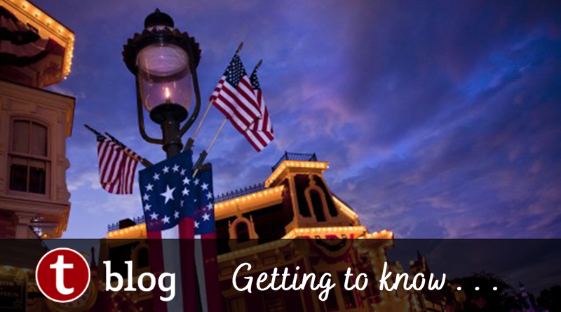 Disney Military Salute Frequently Asked Questions Cover image showing a lamppost in Magic Kingdom with American flags and red-white-blue banners against a dramatic sunset sky.