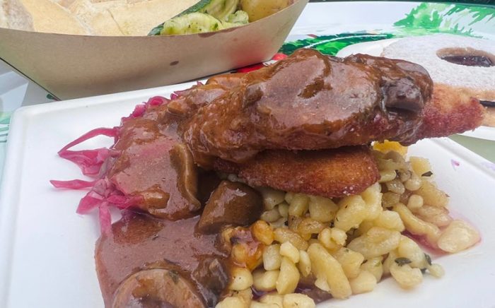 brown, crusty pork schnitzel is piled on a serving of spaetzle and herbs, topped with a generous helping of a rich, brown sauce with slices of sauteed mushroom.