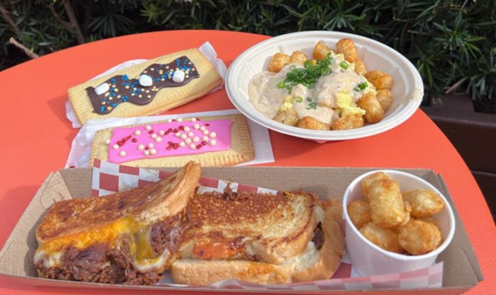 A brisket sandwich with potato barrels, breakfast bowl with potato barrels smothered in gravy, and two lunch box tarts