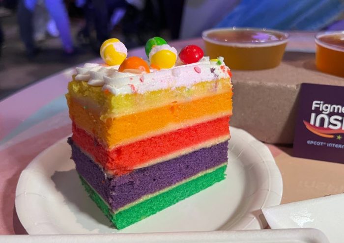 5-layer cake, with each layer a vivid and different color of the rainbow, with white frosting and decorated with Skittles.
