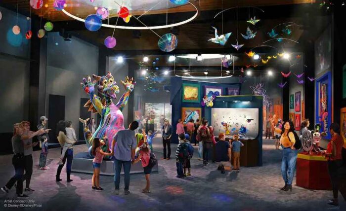 Guests wander around a large open space with mobiles on the ceiling, graphic displays, and a large multi-colored Figment statue